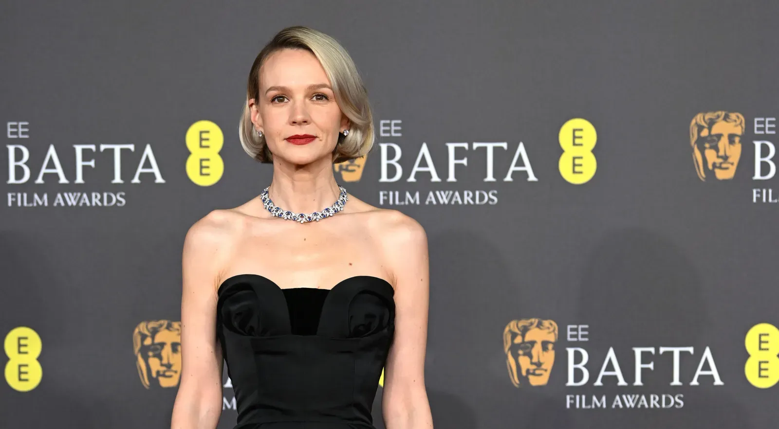 Carey Mulligan stands poised on the BAFTA red carpet, dressed in a custom black Dior Haute Couture gown, paired with a sparkling Bulgari necklace.