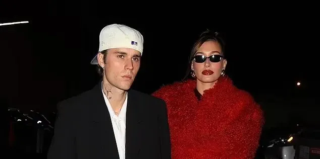 Hailey Bieber in a red Ferragamo mini dress and shearling coat, styled for the Rhode Holiday Party in Los Angeles, embodying festive glamour.
