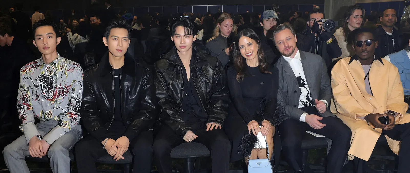 Celebrities Bai Yufan, Li Xian, Metawin Opas-iamkajorn, Lisa Liberati, James McAvoy, and Damson Idris seated in the front row at the Prada FW24 Menswear Fashion Show, each displaying their unique sense of style.