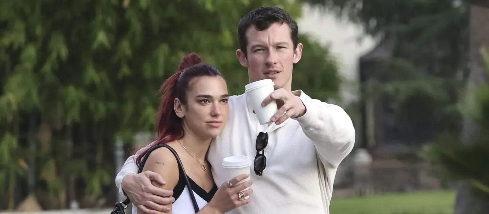 Dua Lipa standing close to a man, both holding coffee cups, with Dua Lipa carrying a Bottega Veneta Gemelli Medium bag.