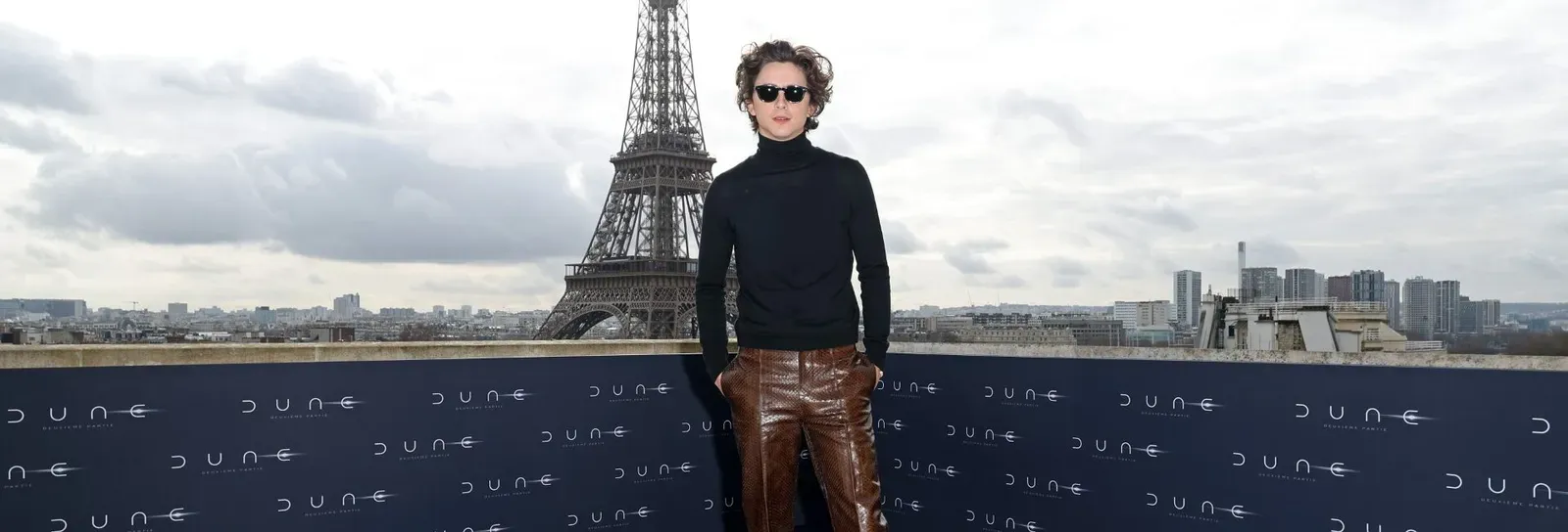 Timothée Chalamet at the 'Dune: Part 2' Paris photocall against a backdrop of the Eiffel Tower, wearing Bottega Veneta.
