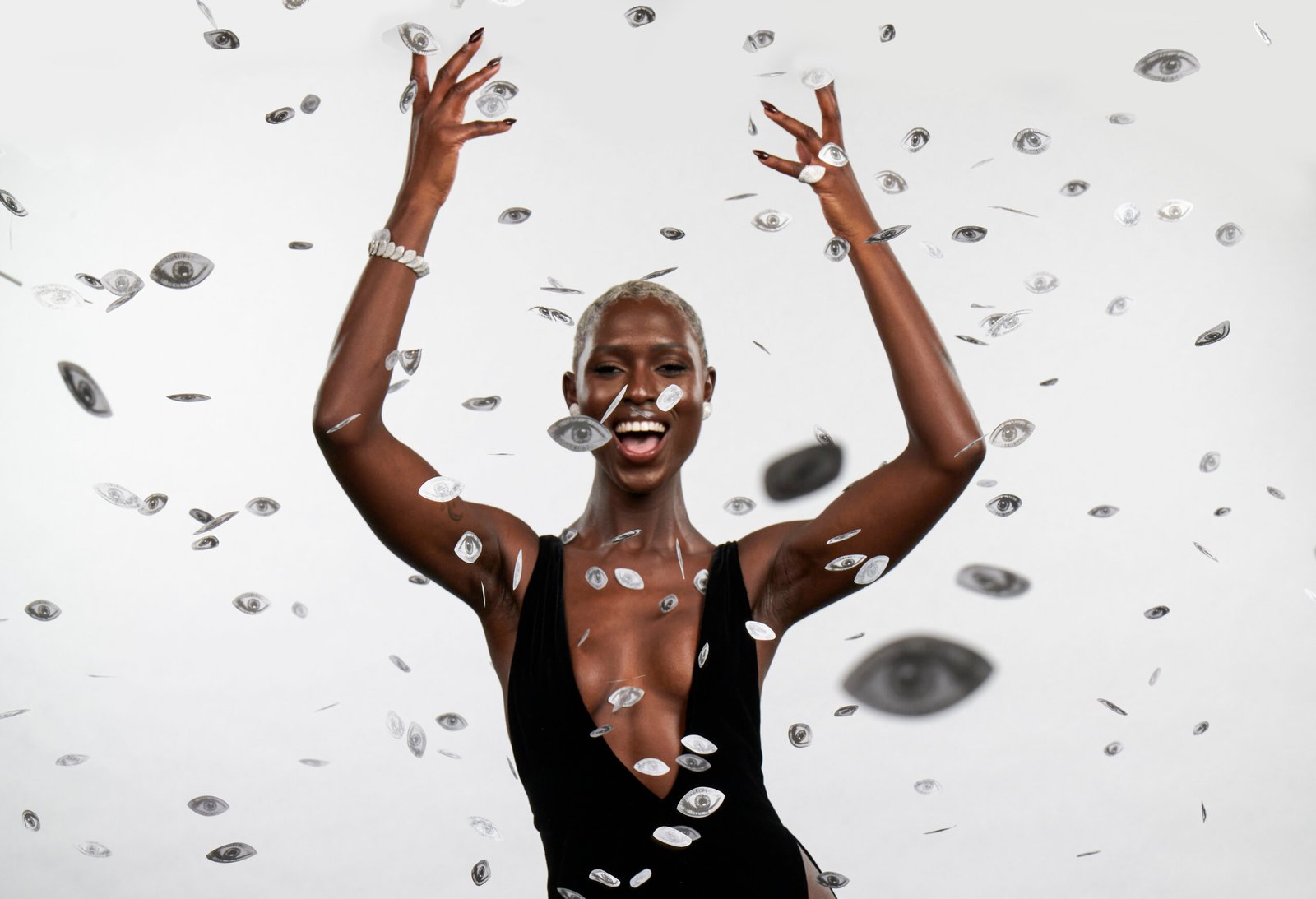 Jodie Turner-Smith joyously throws her arms up, surrounded by a shower of silver confetti coins, capturing a moment of celebration and exuberance at an Oscars' after-party.