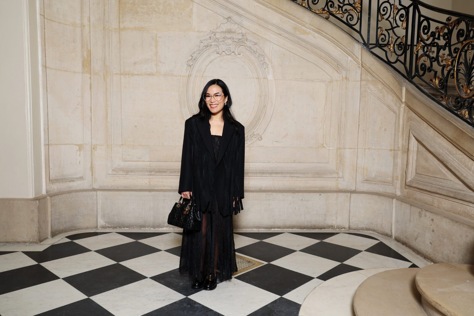 Ali Wong wore a Dior Spring-Summer 2024 black silk fringed coat and dress and a Dior bag and shoes.