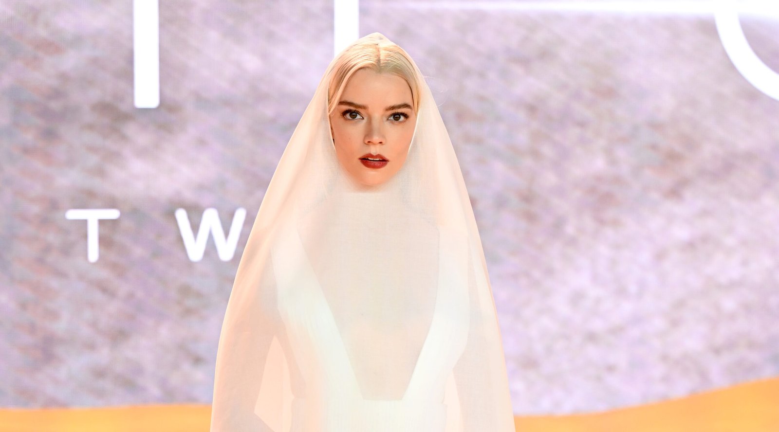 Anya Taylor-Joy stands enveloped in a flowing white cotton organdie cape over a silk pleated dress by Dior Haute Couture at the "Dune: Part Two" world premiere in Leicester Square.