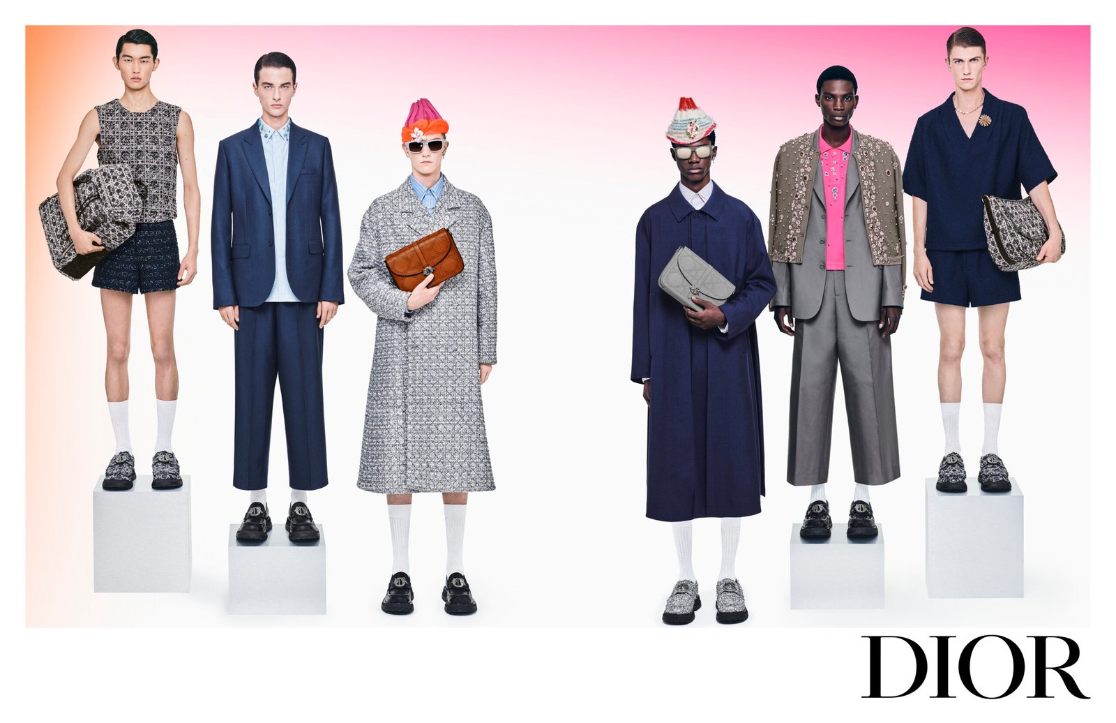 A group of five male models showcasing an array of DIOR men's fashion SS24, featuring a mix of casual and formal wear, accessorized with various bags, and standing against a pink gradient background with the DIOR logo below.