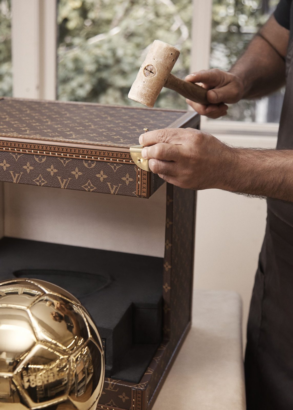 A Louis Vuitton artisan at the Asnières workshop demonstrates the traditional craftsmanship involved in creating the Ballon d'Or Trophy Trunk. (Photo: Courtesy of Louis Vuitton)