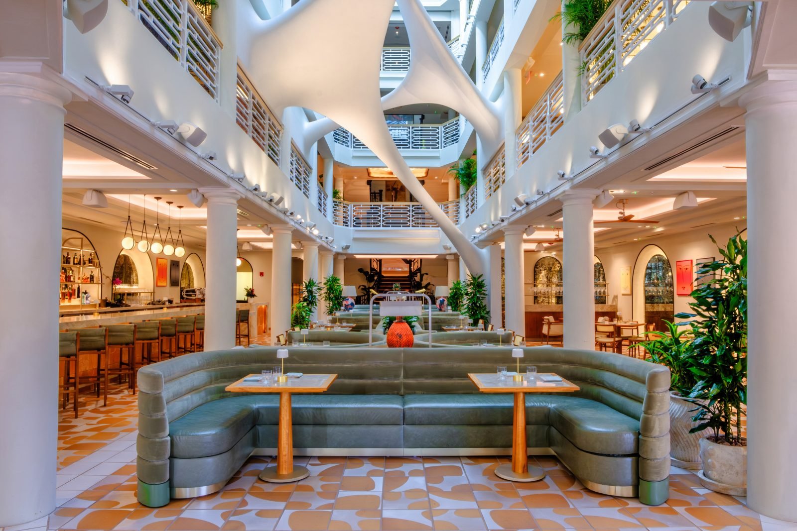 Interior view of Elastika in the historic Moore Building, where sleek, sage banquettes and geometric floor patterns complement the soaring white columns, creating a seamless fusion of contemporary design and architectural heritage.