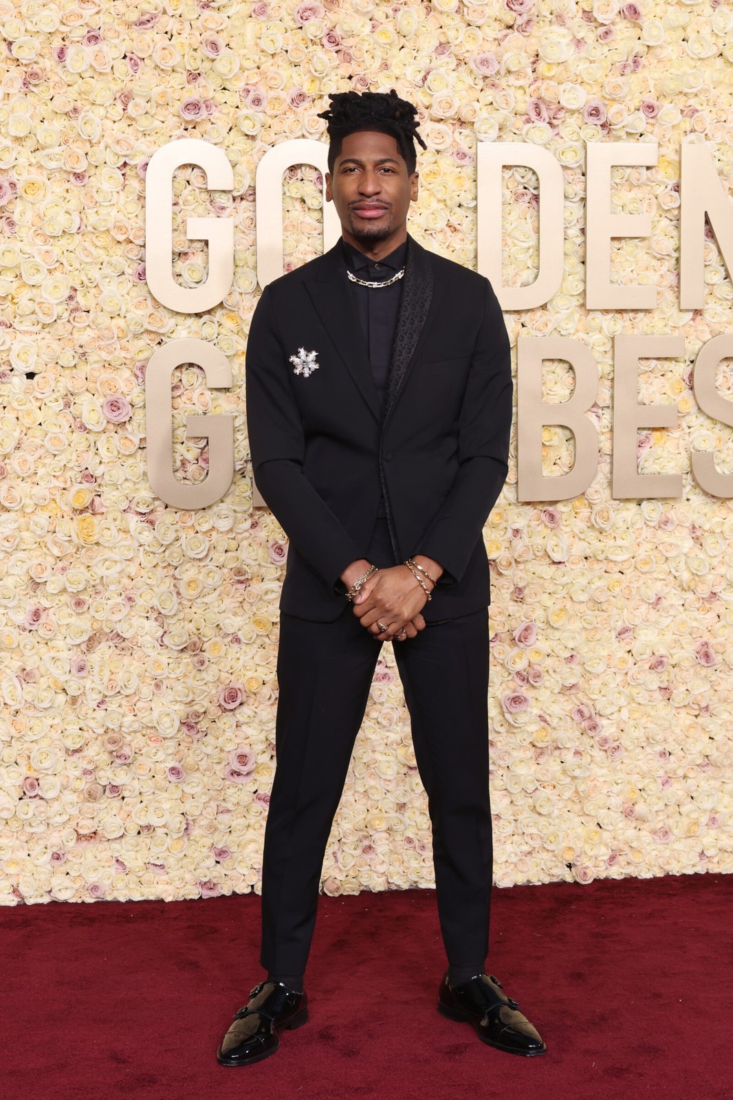 Jon Batiste, in his signature style, exudes confidence in a Dior Men's black wool twill oblique asymmetric suit with a shawl collar, paired with a classic black cotton tuxedo shirt. (Photo by Amy Sussman/Getty Images)