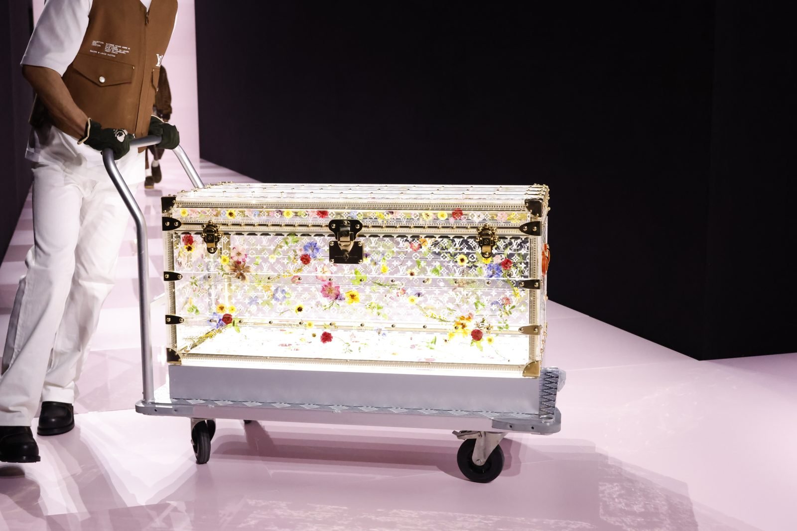 An elaborate, transparent Louis Vuitton trunk is showcased during the Men's FW25 show in Paris, highlighting the maison's time-honored savoir-faire and the excellence of its signature heritage trunk (Photo: Courtesy of Louis Vuitton).