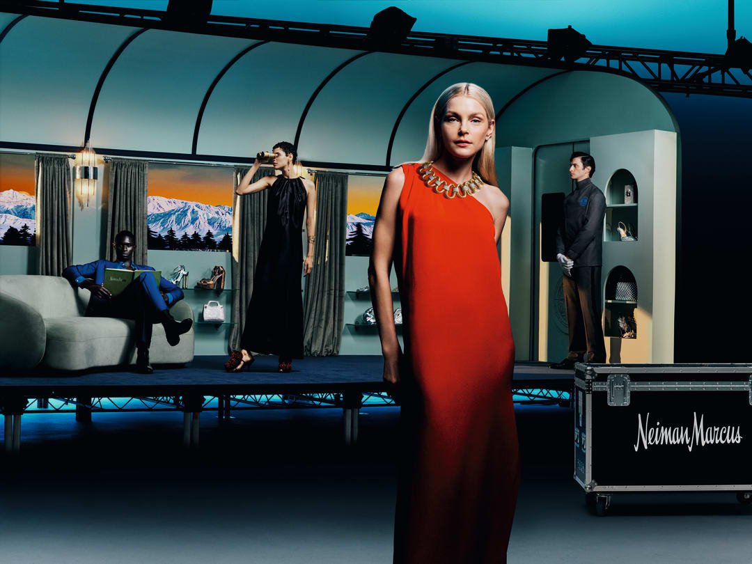 A vibrant Neiman Marcus holiday campaign scene featuring a diverse group of models in a stylized set with alpine backdrops, showcasing the season's gifts and fashion.