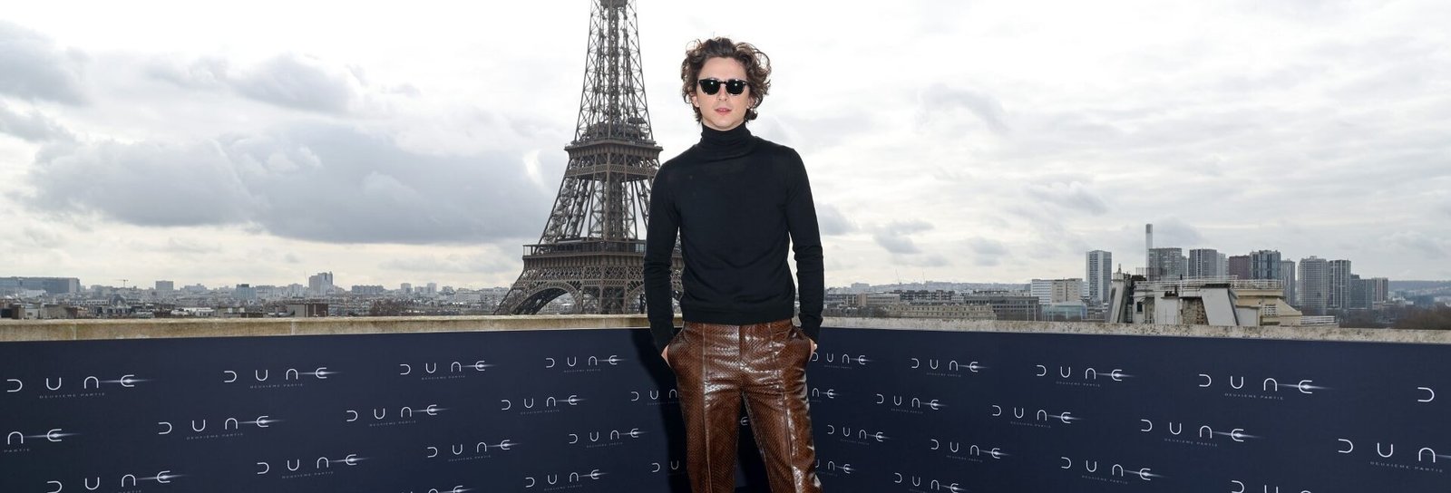 Timothée Chalamet at the 'Dune: Part 2' Paris photocall against a backdrop of the Eiffel Tower, wearing Bottega Veneta.
