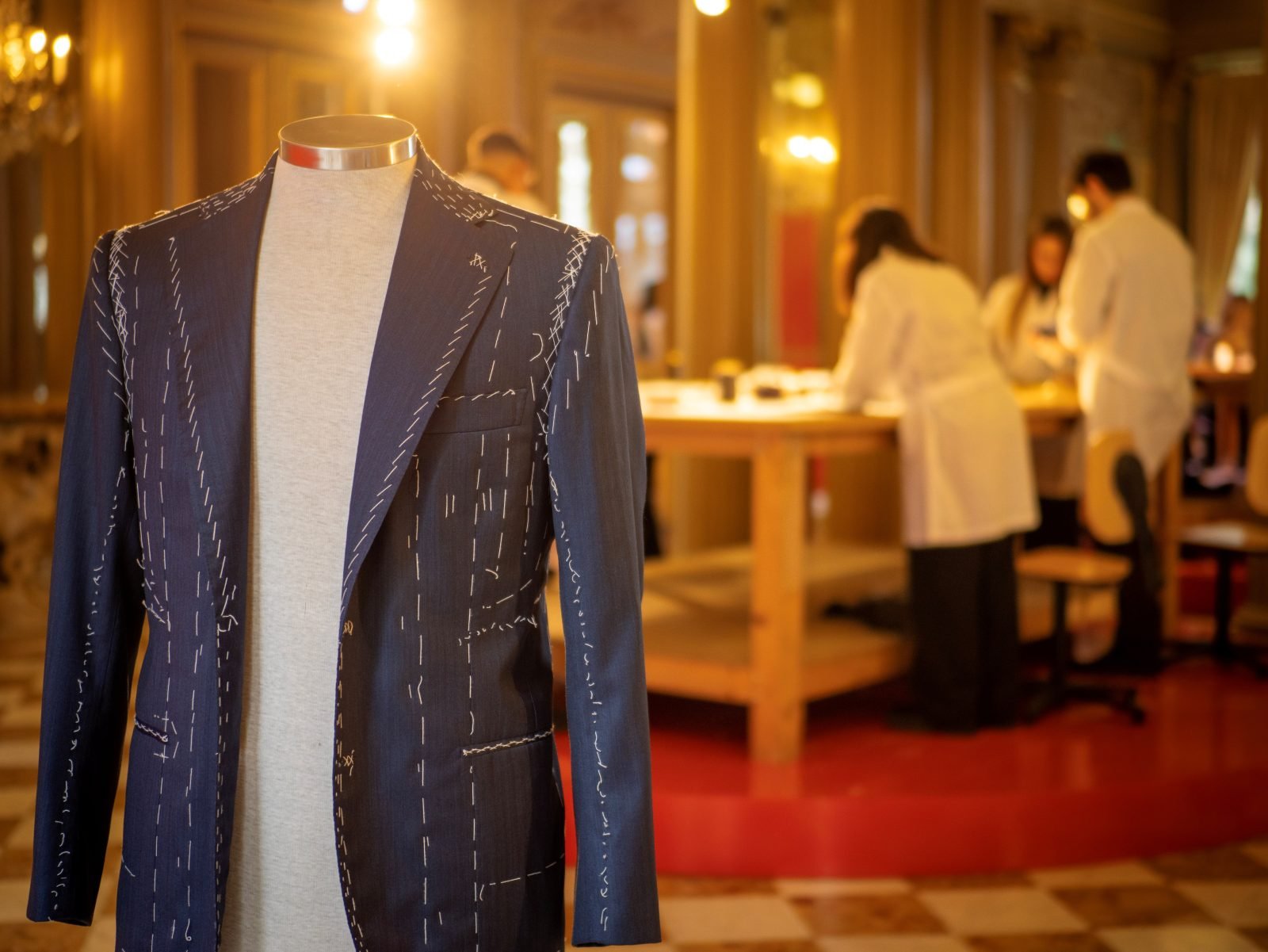 A basted suit jacket on display at the Istituto Italiano di Cultura di Parigi showcases the intricate handwork behind Kiton's tailoring, with students working in the background. (Photo: Courtesy of Kiton)