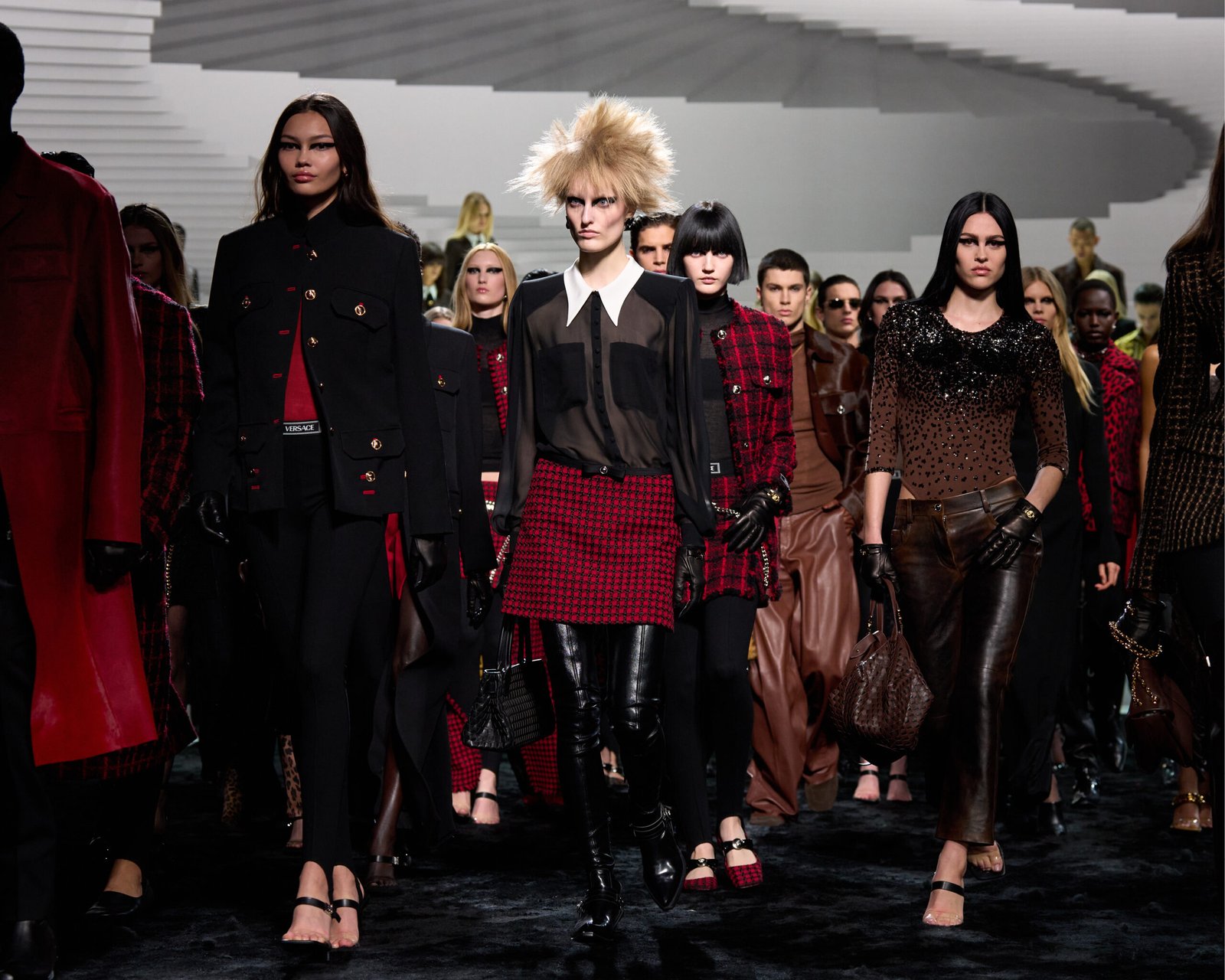 Models stride down the runway in Versace's Autumn/Winter 2024 collection at Milan Fashion Week, showcasing a blend of rebellion and luxury with tailored coats, metal mesh fabrics, and bold colors.
