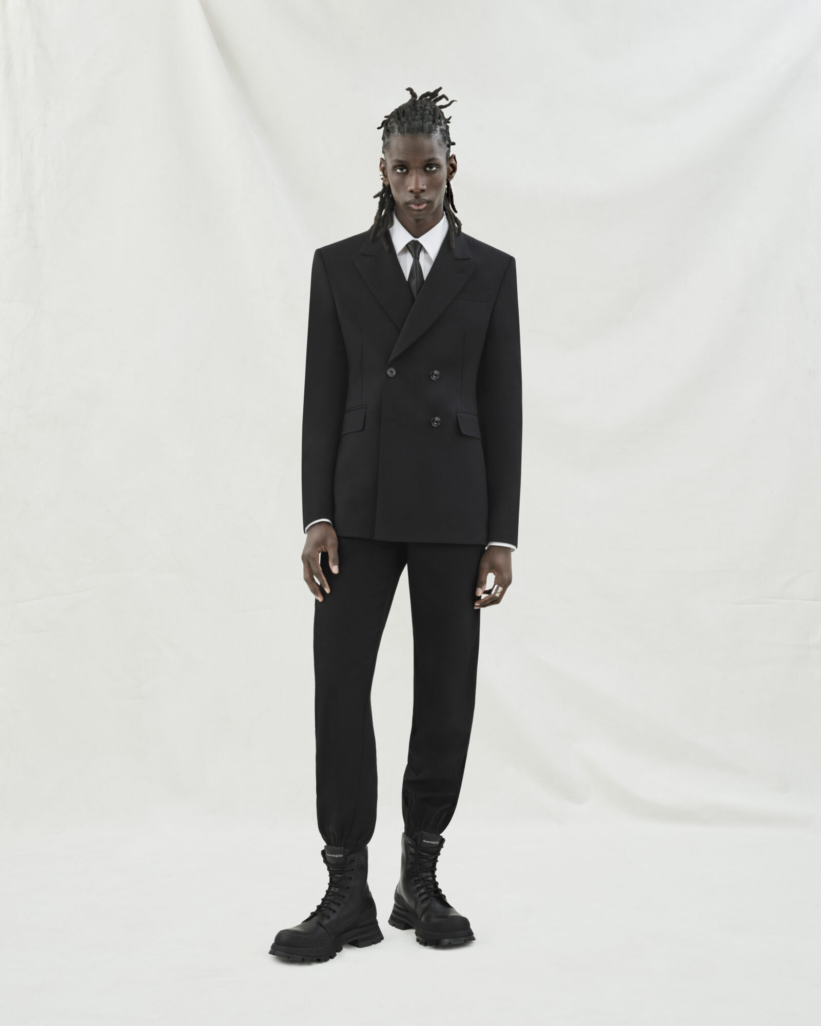 Look 01: Double-breasted jacket and cargo trousers in rich black wool gabardine. Look 01: Double-breasted jacket and cargo trousers in rich black wool gabardine.