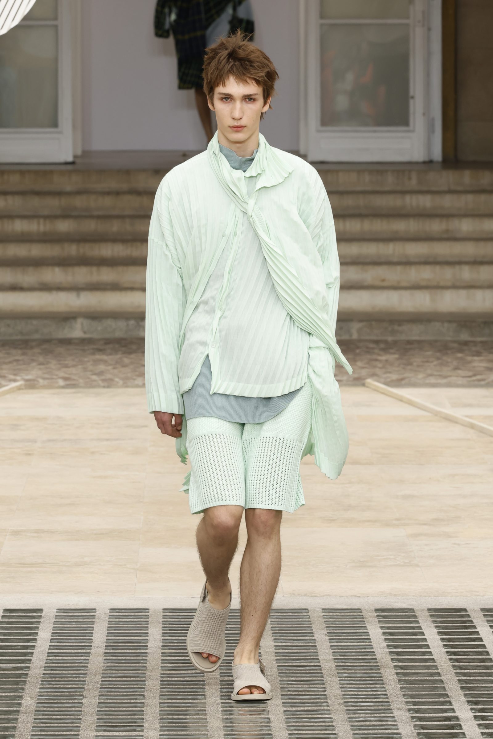 WINDSWEPT SHIRT is a lightweight hand-pleated series made in simple silhouettes, with curved pleats creating windblown waves. The design features an extended necktie that can be tied or draped around, adding to the feeling of things swaying in the wind.