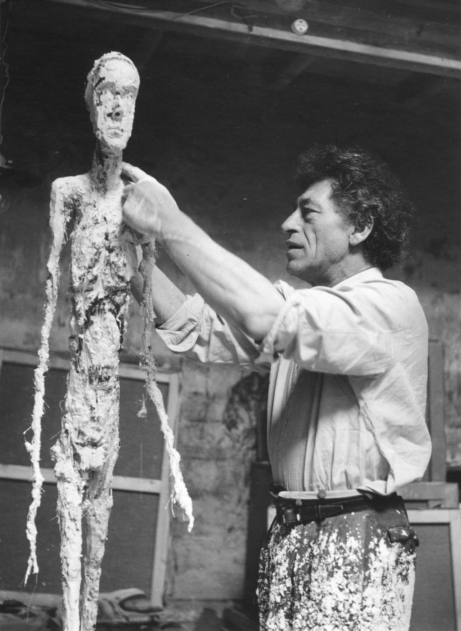 Ernst Scheidegger, Alberto Giacometti Working on the Plaster of the “Walking Man,” c. 1959, silver print on paper, Archives, Fondation Giacometti. © 2022 Artists Rights Society (ARS), New York / ProLitteris, Zurich Ernst Scheidegger, Alberto Giacometti Working on the Plaster of the “Walking Man,” c. 1959, silver print on paper, Archives, Fondation Giacometti. © 2022 Artists Rights Society (ARS), New York / ProLitteris, Zurich