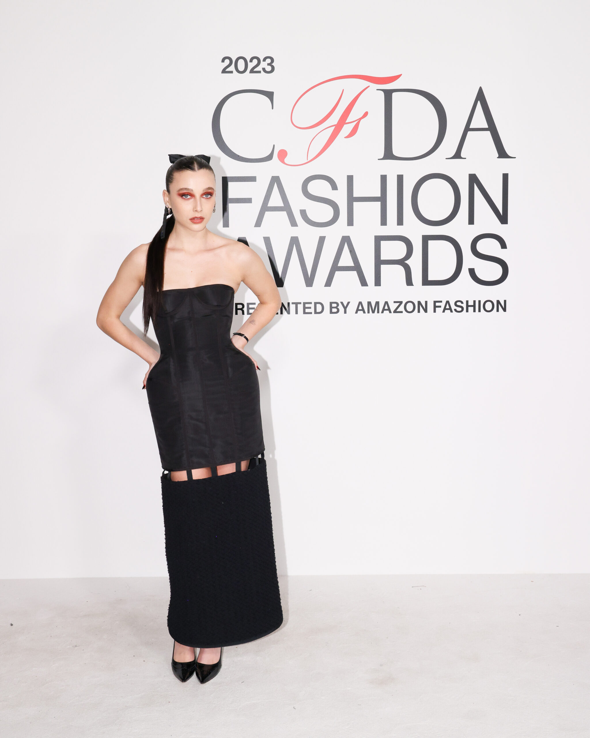 Emma Chamberlain strikes a pose at the CFDA Fashion Awards 2023, showcasing the bold elegance of a Thom Browne structured corset dress, complemented by a sleek hairstyle and statement makeup. Emma Chamberlain strikes a pose at the CFDA Fashion Awards 2023, showcasing the bold elegance of a Thom Browne structured corset dress, complemented by a sleek hairstyle and statement makeup.