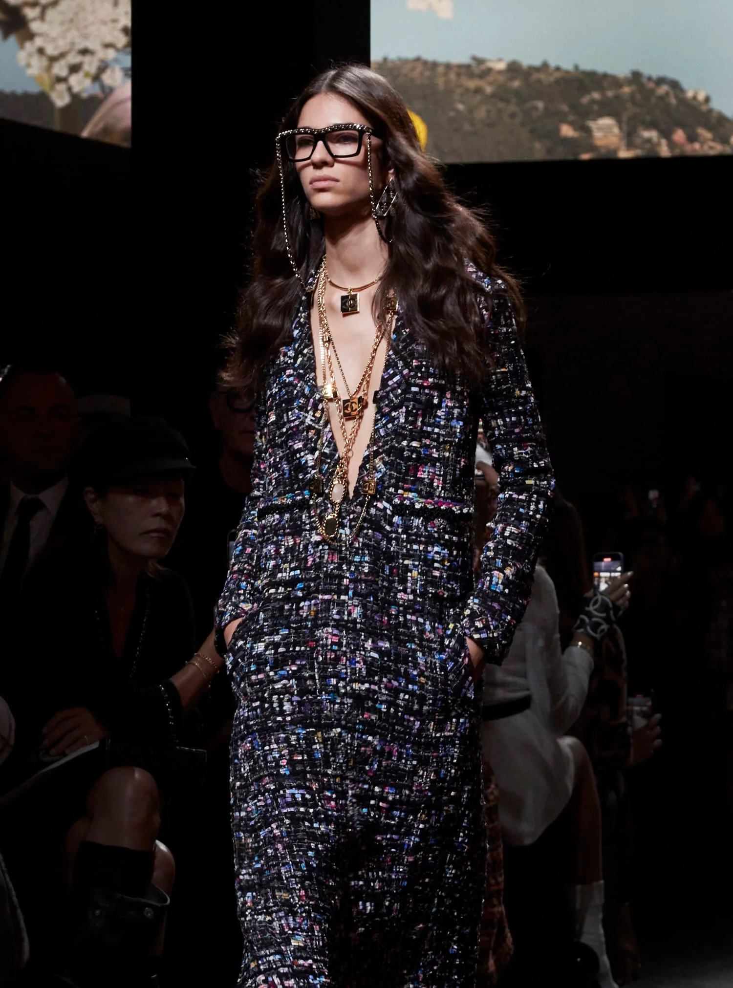 The stained glass-inspired Chanel jumpsuit adorned with signature jewelry sets the tone for a playful high-fashion fusion. A model dons the stained glass-inspired Chanel jumpsuit, adorned with the house