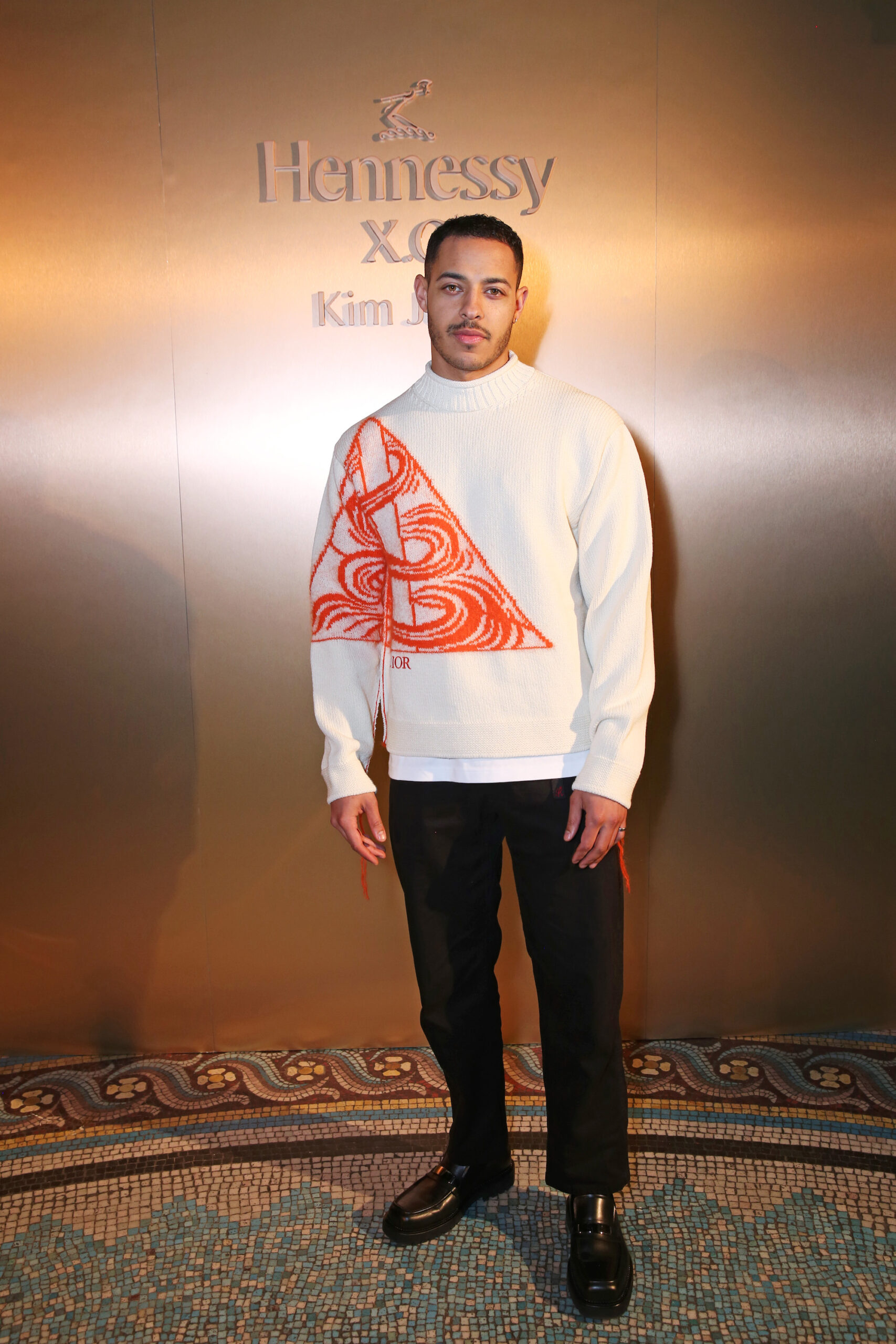 Daryl McCormack wore a Dior Fall 2023 men’s collection white blended wool and mohair crewneck, asterodior placed jacquard, a black wool pant, a white cotton t-shirt and black leather derbies. Daryl McCormack