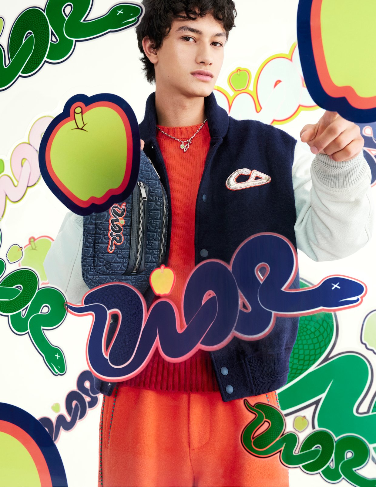 Set against KAWS's playful apple and snake motifs, varsity jackets in navy and red demonstrate the collection's masterful balance of sophistication and street culture (Photo: Courtesy of Dior)