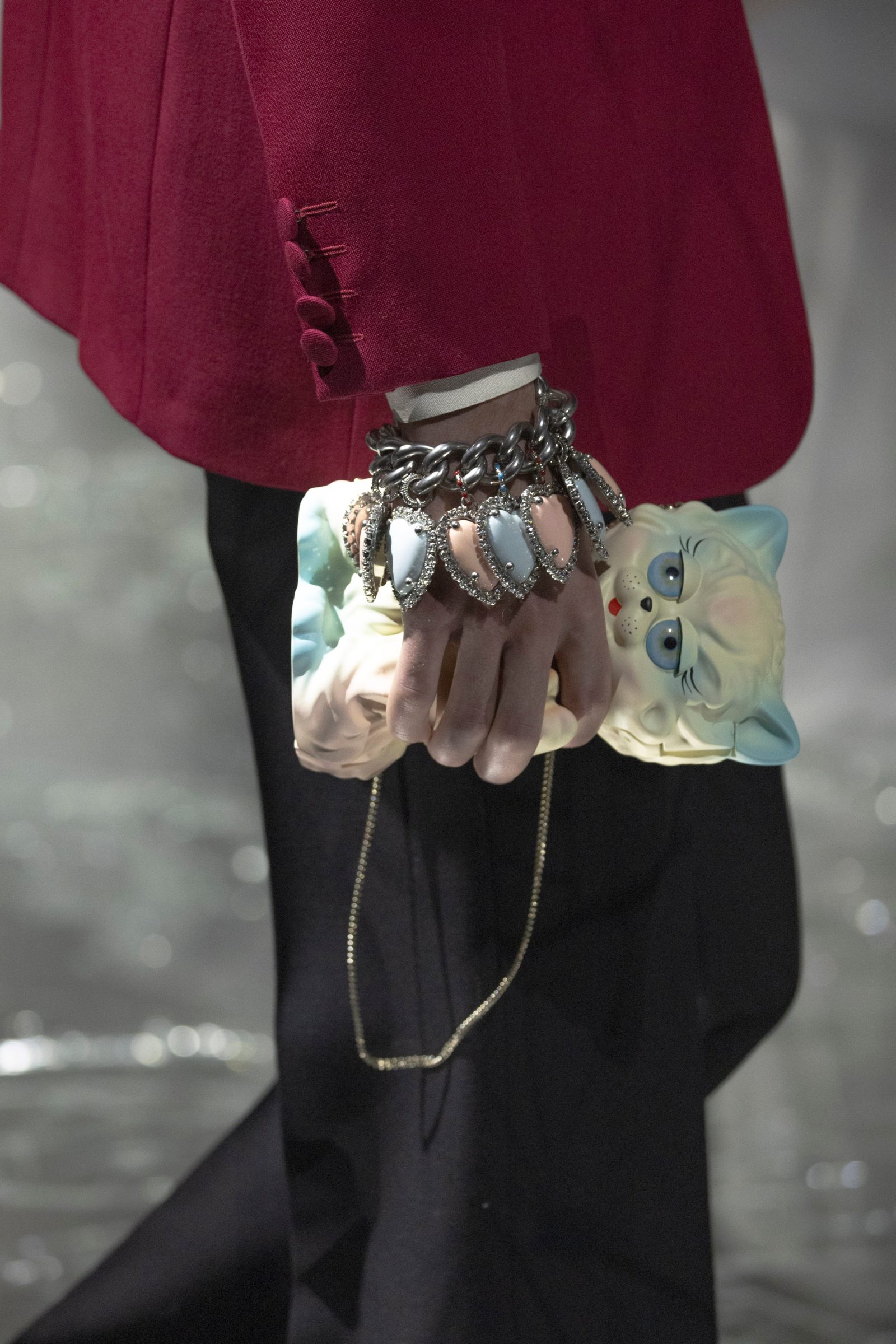 A touch of humor: a whimsical cat clutch embellished with porcelain-like finish carries a crystal chain, while a dramatic silver chain bracelet finished with mother-of-pearl hearts adds edge to a burgundy sleeve.