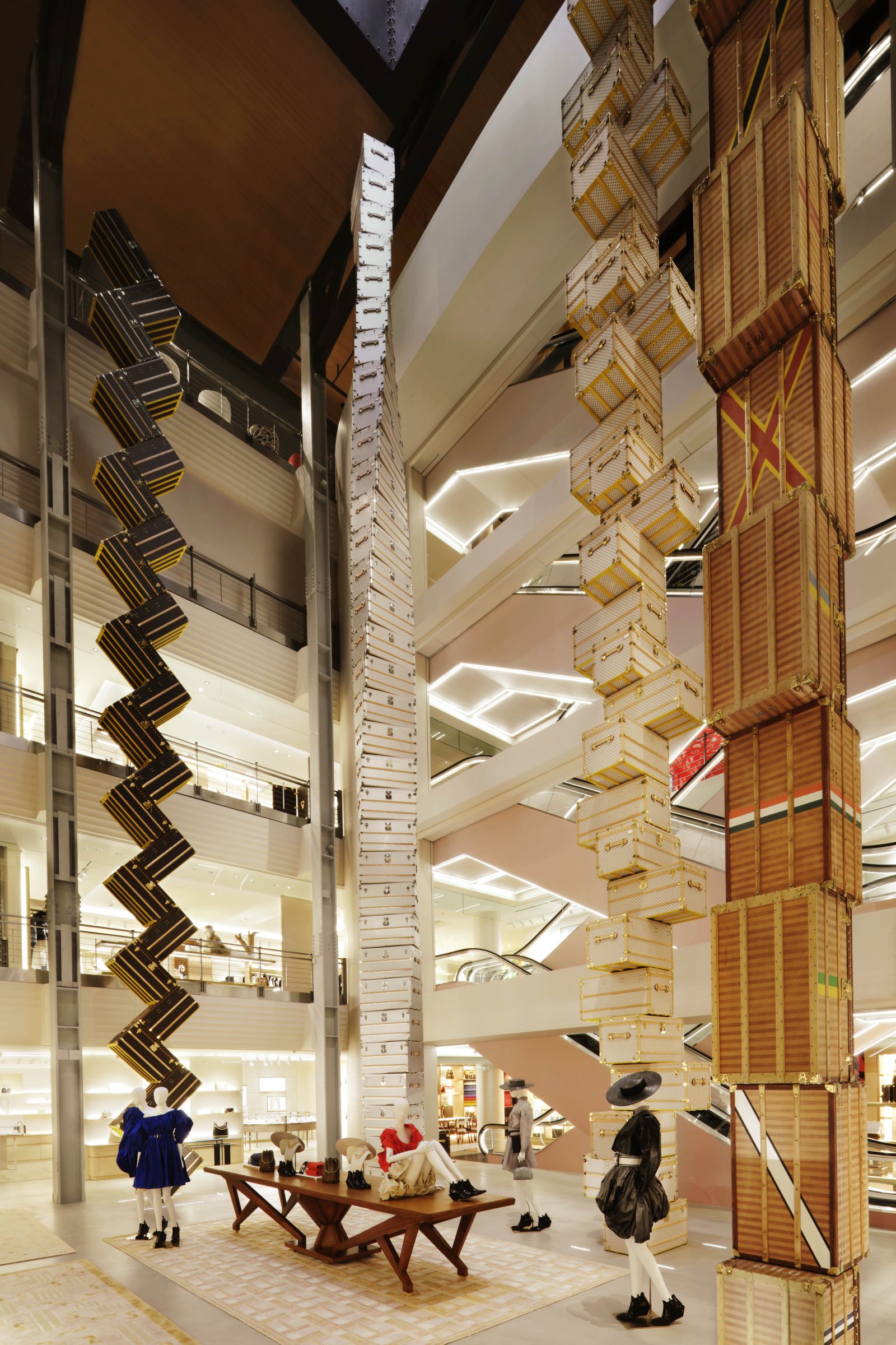 The central atrium showcases a striking installation of four trunk towers, each featuring distinct Louis Vuitton materials, alongside mannequins displaying the latest collections. (Imagery: Courtesy of Louis Vuitton)