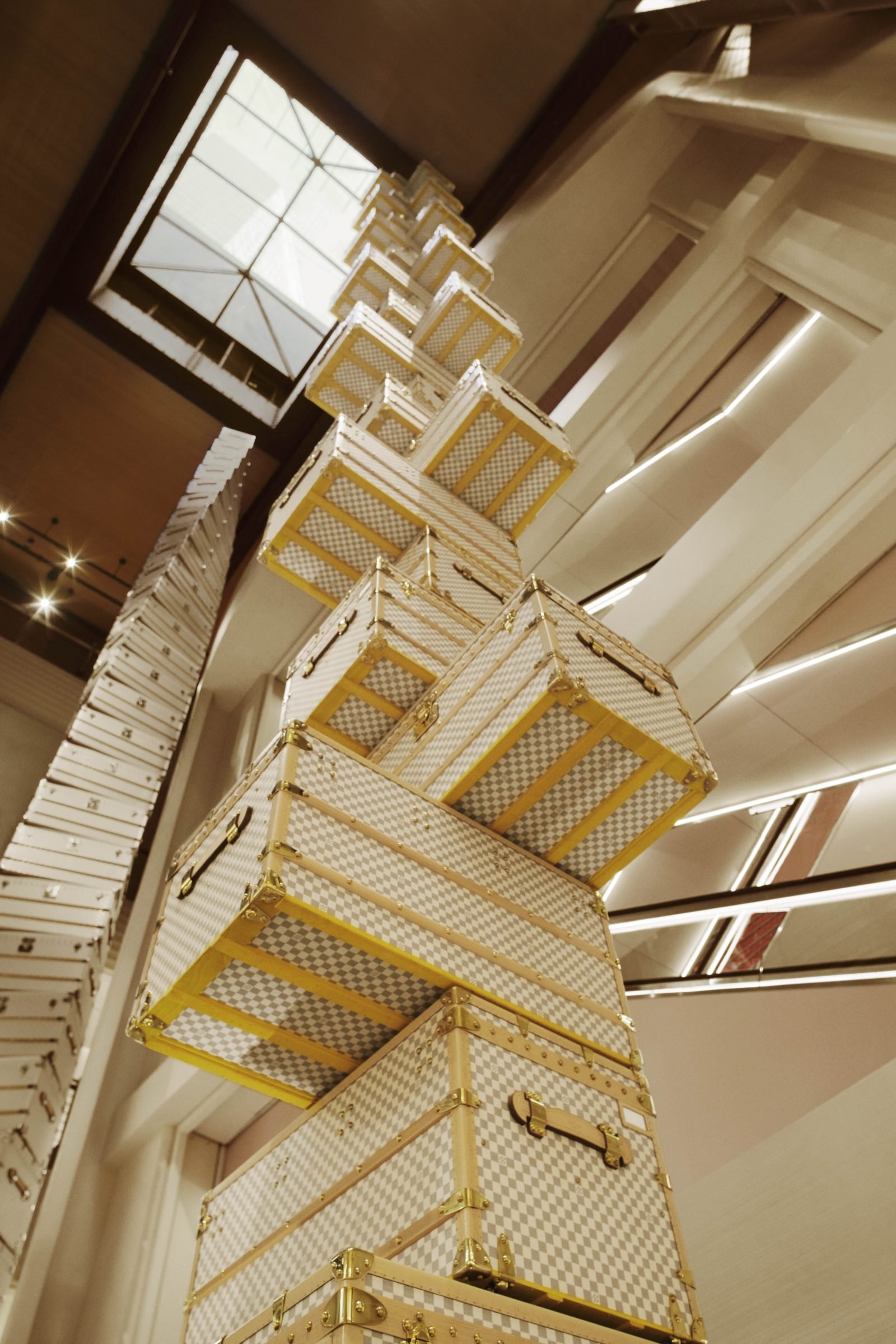 One of four dramatic trunk towers by OMA's Shohei Shigematsu, featuring the white Damier pattern, soaring 16 meters in the store’s grand atrium.