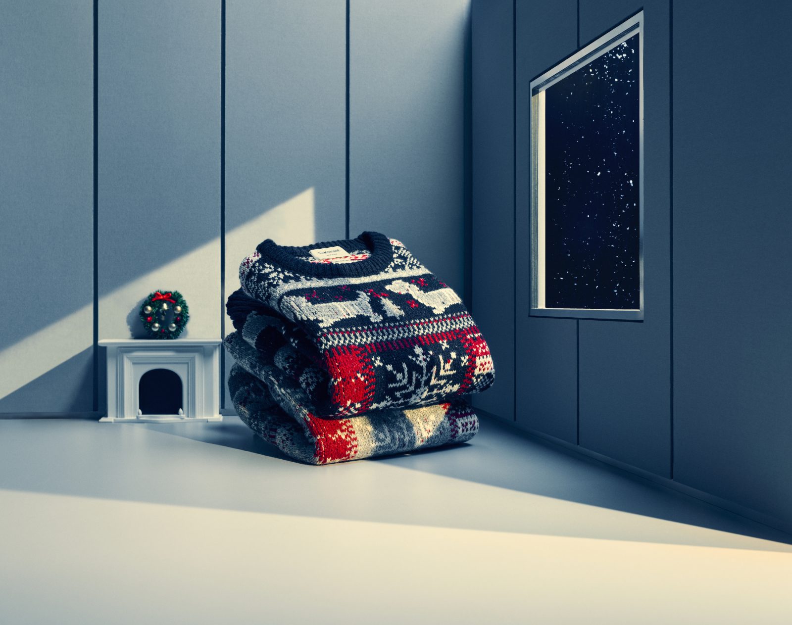 Hector Pullover sweaters, adorned with playful dachshund motifs, rest beside a miniature fireplace mantle and a window filled with celestial wonder—whimsically enhancing Browne’s festive holiday narrative. (Image: Courtesy of Thom Browne)