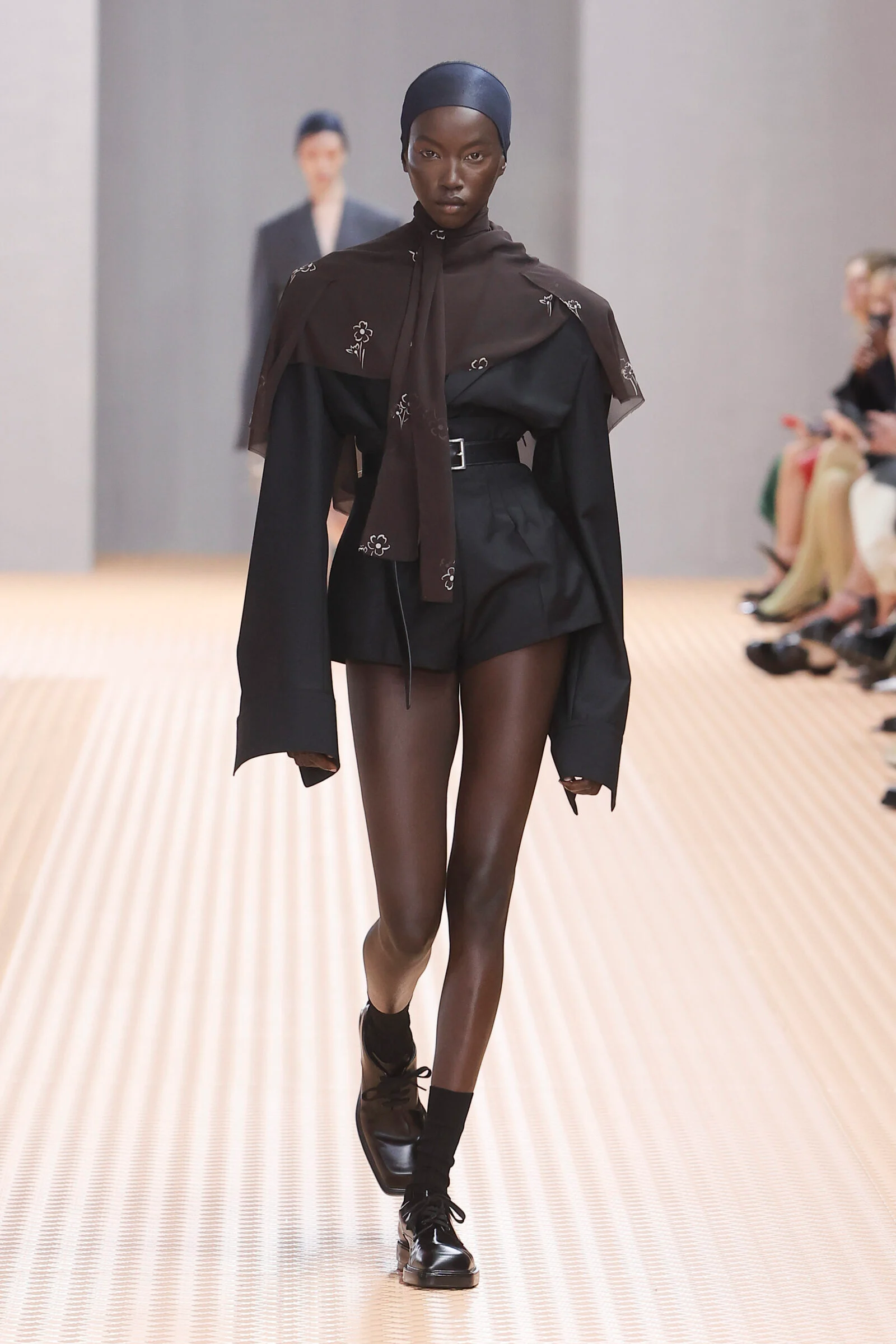 Structural Innovation: Prada SS24 reimagines power dressing with a dramatic play on classic tailoring, blending tradition with contemporary edge.