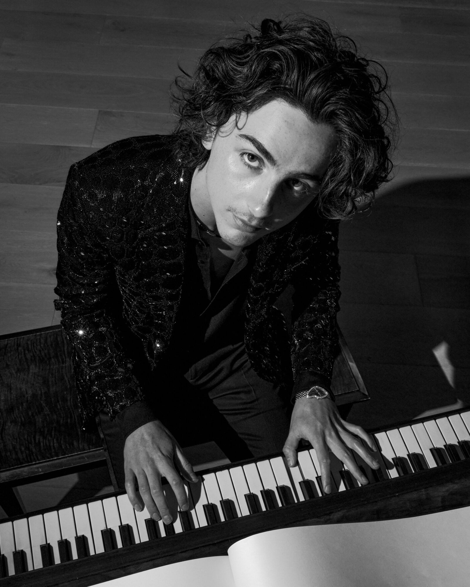 Backstage Brilliance: Timothée Chalamet strikes a reflective pose at the piano, dressed in CELINE HOMME's exquisite textures, captured by Julian Ungano.