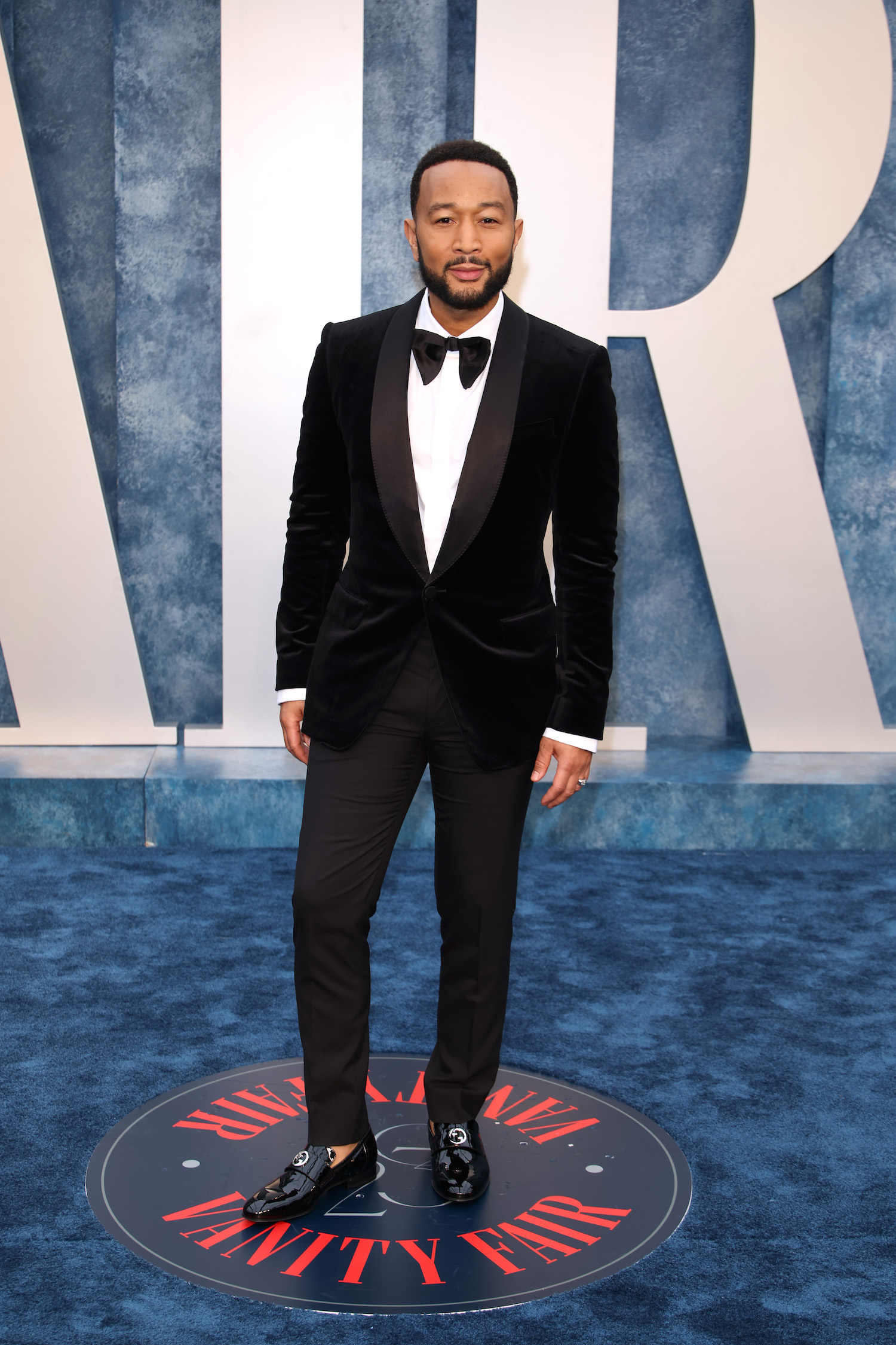 John Legend wore a black Gucci velvet tuxedo, white evening shirt, black bowtie, and black patent leather loafers.