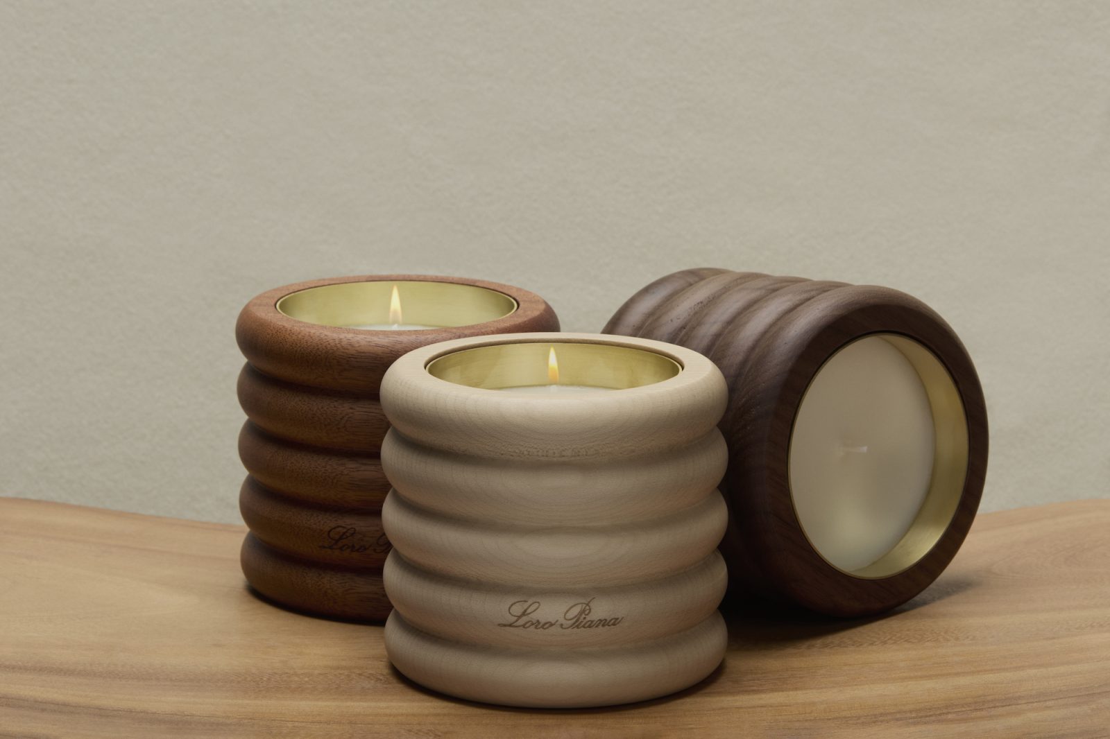The new Loro Piana candle collection: Mystic Fleece, Cashfur Cloud, and Smoky Tweed, housed in carved wooden vessels that echo the house's textile heritage. (Image: Courtesy of Loro Piana)