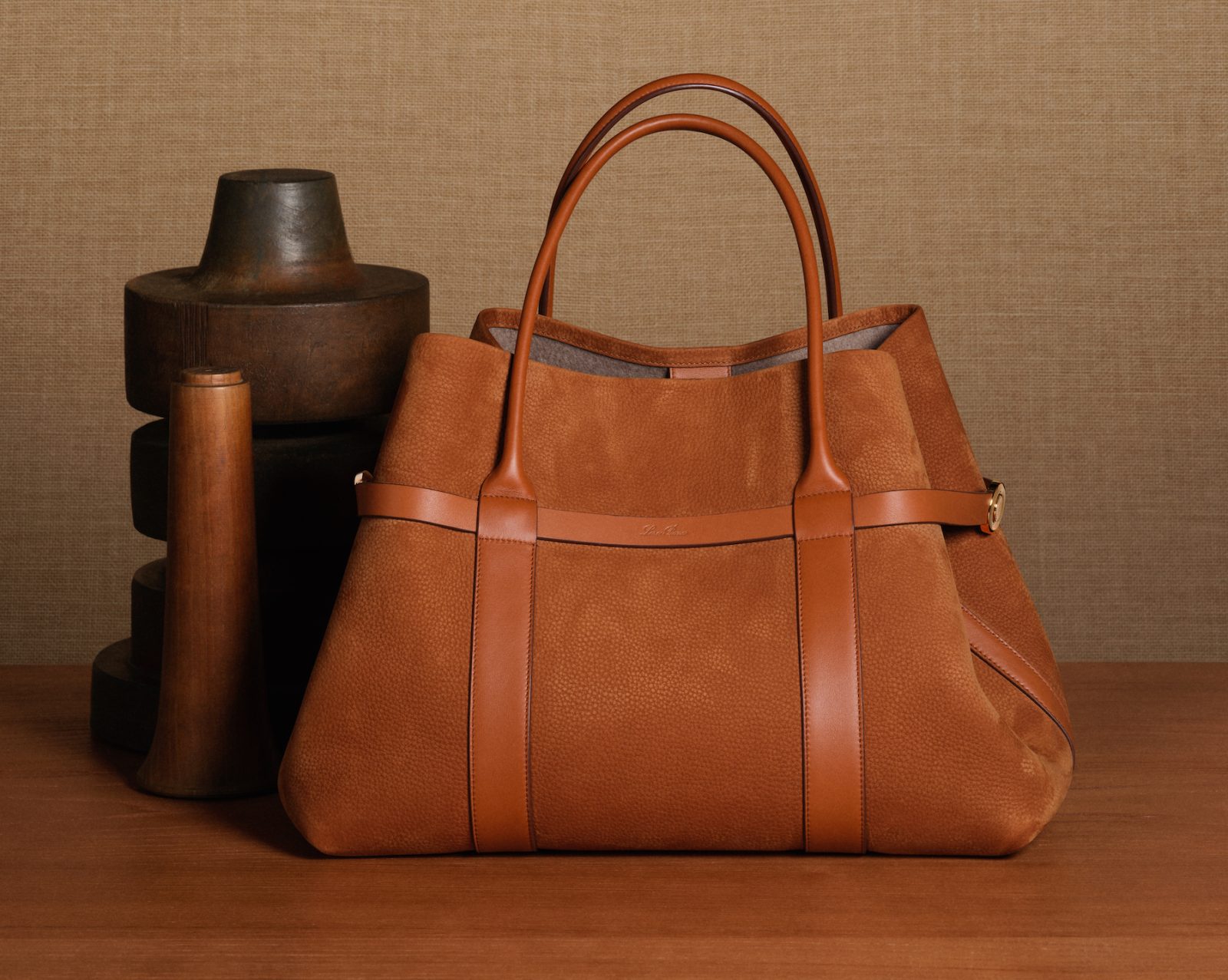 The Ghiera Shopper in grained leather, shown alongside artisanal wooden forms, highlighting its refined craftsmanship and architectural silhouette.
