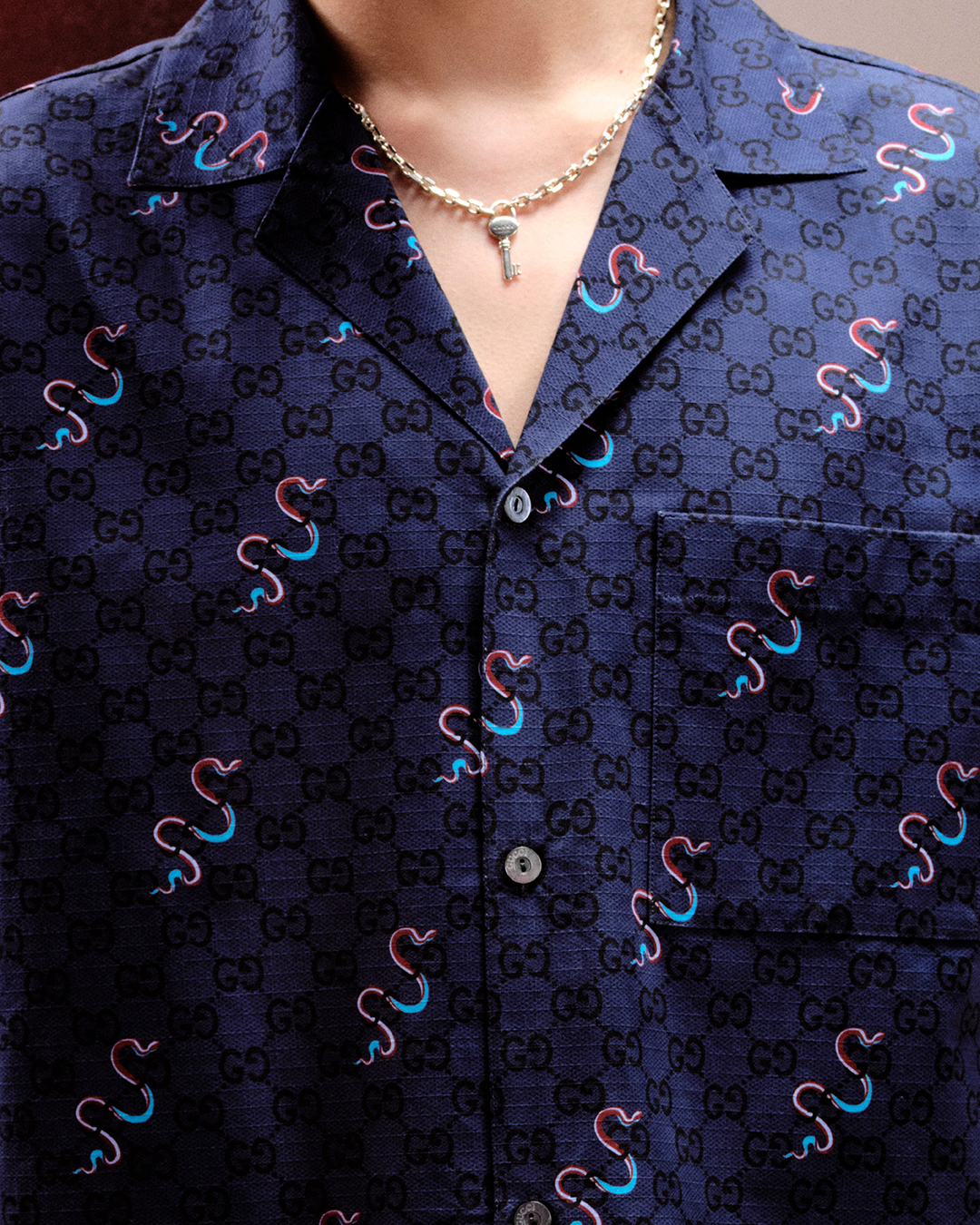 Detail of the snake motif intertwining with the GG monogram on navy silk, showing the Rosso Ancora and blue color combination. (Image: courtesy of Gucci)