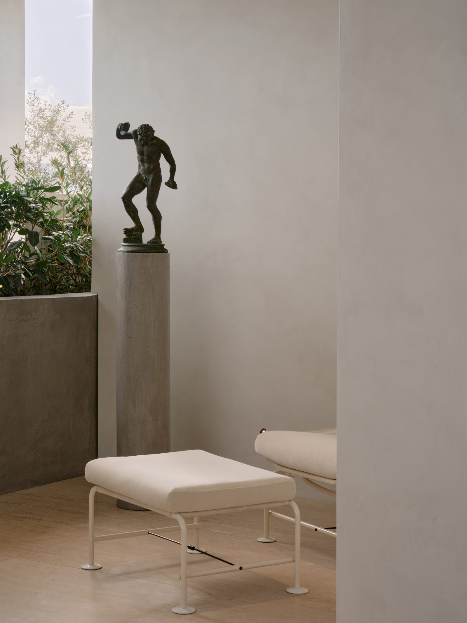 A modernist white ottoman rests beneath a classical bronze sculpture in the new boutique, where architectural elements form a subtle dialogue between contemporary and classical design. (Image: Courtesy of Saint Laurent)