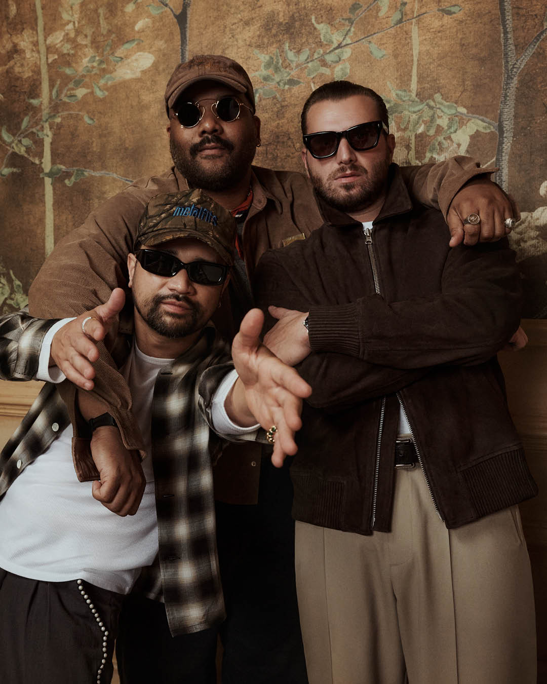 Three trendsetters unite, exuding effortless style and camaraderie against a vintage backdrop.